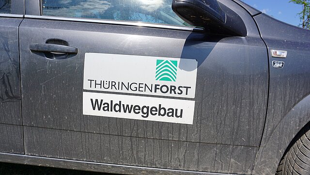 Eine Fahrzeugseite mit ThüringenForstaufkleber und der Aufschrift Wegebau.