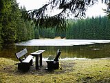 Linkziel: Link zum Beitrag mit dem Thema Zugefrorene Waldteiche nicht betreten; Bildinhalt: Eine Sitzgruppe aus Holz an einem halb zugefrorenem See im Wald.