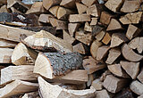 Linkziel: Link zum Beitrag mit dem Thema Brennholznutzer sollten sich nicht verunsichern lassen ; Bildinhalt: Blick auf einen Brennholzstapel, davor liegen einzelne Holzscheite