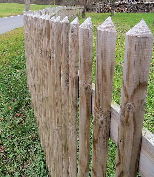 Ein Zaun aus Holzlatten mit angespitzten Enden am oberen Ende