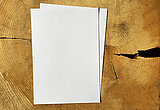 Zwei Blatt weißes Schreibpapier liegen auf einer Holzscheibe